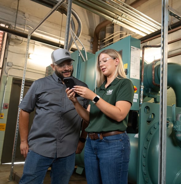 EHS manager works with HVAC maintenance professional with commercial equipment in background