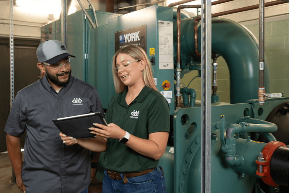 HVAC maintenance technician and environmental, health and safety manager discuss project with commercial equipment in background