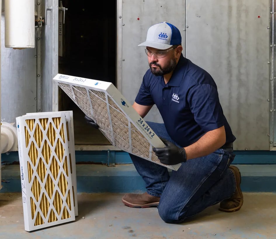 Commercial HVAC technician in dark blue polo shirt changes a filter