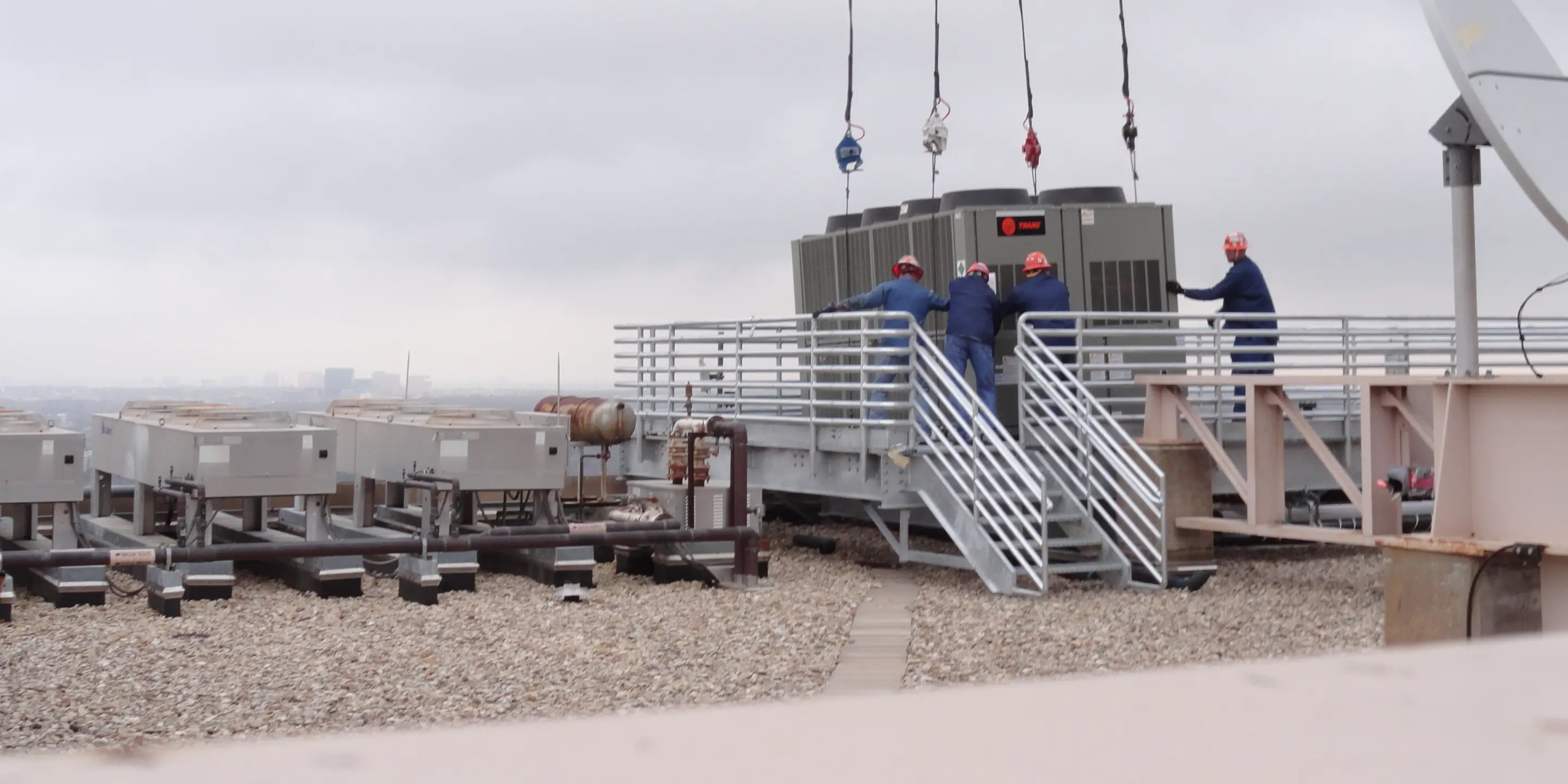 TDIndustries construction team guides rooftop HVAC equipment in place during a helicopter lift